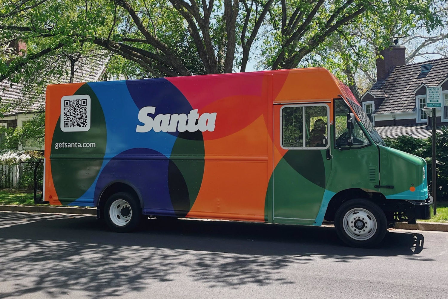 A giant, colorful truck in front of a tree.